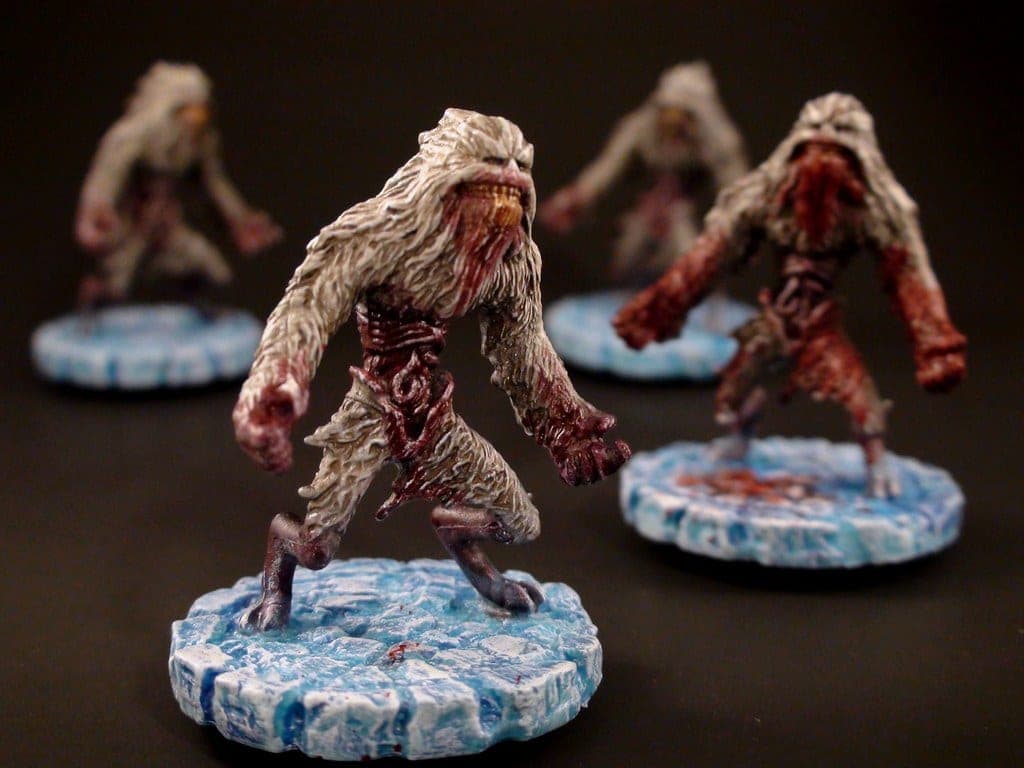 A painted miniature on a hobby desk beside brushes and paint pots